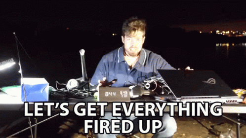 A Man Sitting At A Table With A Laptop And A Sign That Says 8:44 GIF