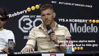 A Man Sitting At A Table With A Microphone In Front Of A Sign That Says Modelo GIF