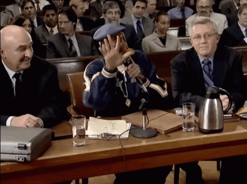 A Man Sitting At A Table With A Microphone In Front Of Him GIF