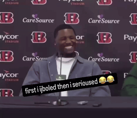 a man sitting at a table with a sign that says " first ijboled then i serious "