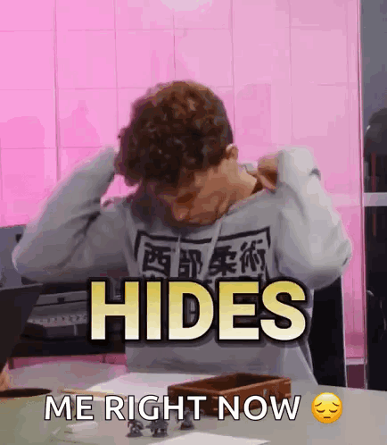 A Man Sitting At A Table With His Hands On His Head And The Words Hides Me Right Now GIF