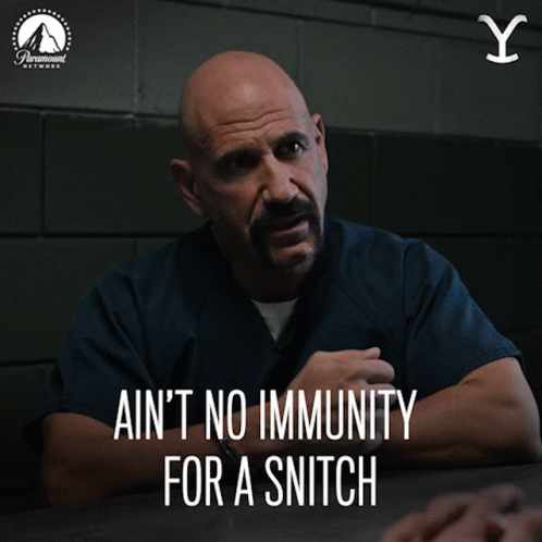 A Man Sitting At A Table With The Words " Ain 'T No Immunity For A Snitch " Below Him GIF