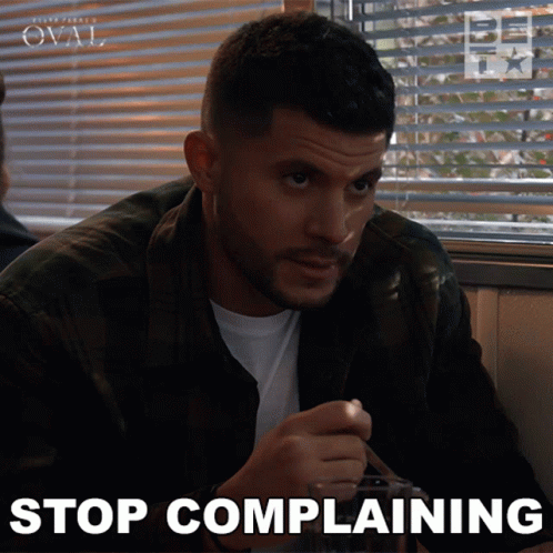 A Man Sitting At A Table With The Words Stop Complaining On The Bottom Right GIF