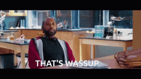 A Man Sitting At A Table With The Words That 'S Wassup Written On The Bottom GIF