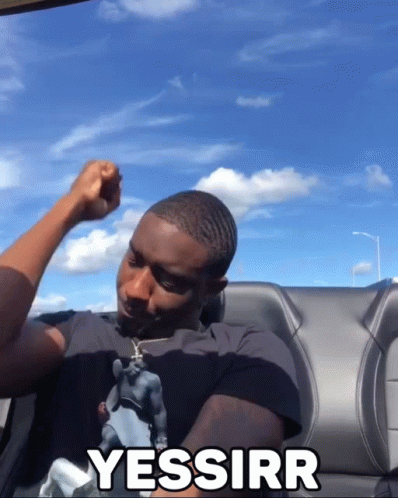 A Man Sitting In A Car With His Fist In The Air And The Word Yessirr Written On The Back GIF