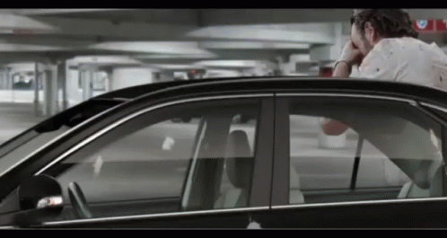 A Man Sitting In A Car With His Head In His Hand GIF