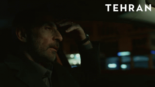 A Man Sitting In A Car With Tehran Written On The Bottom GIF