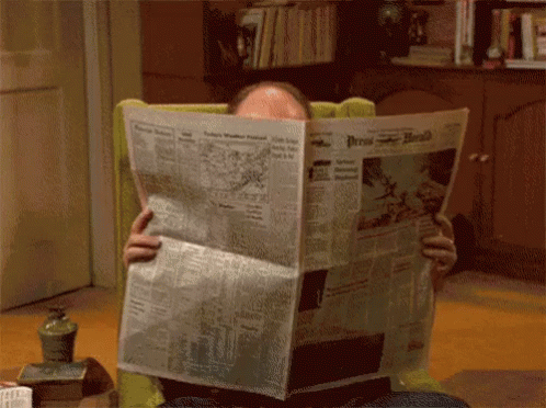 A Man Sitting In A Chair Reading The Press Herald GIF