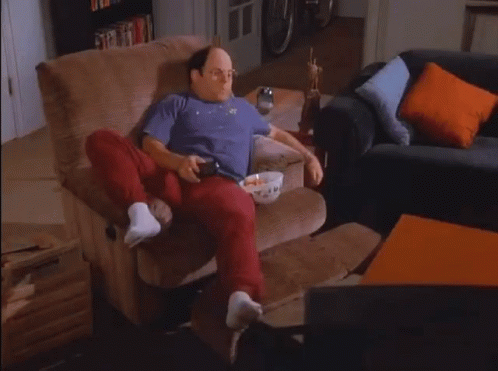 A Man Sitting In A Chair With A Bowl Of Popcorn On His Lap GIF