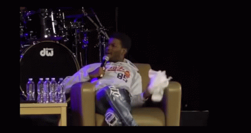 A Man Sitting In A Chair With A Microphone In Front Of A Drum That Says Dw On It GIF