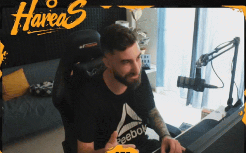 A Man Sitting In A Chair With A Reebok Shirt On GIF