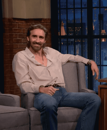 a man sitting in a chair with his arm resting on the arm rest