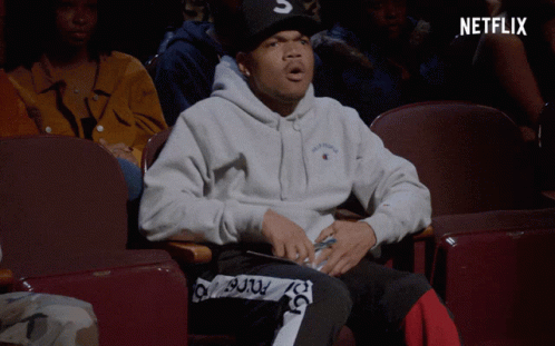 A Man Sitting In A Theatre With A Netflix Logo On The Bottom GIF