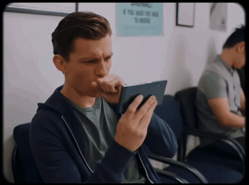 A Man Sitting In A Waiting Room With A Sign On The Wall That Says Please GIF