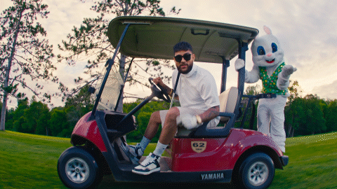 A Man Sitting In A Yamaha Golf Cart Next To A Stuffed Rabbit GIF