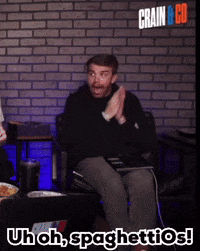 A Man Sitting In Front Of A Brick Wall With The Words Uh Oh Spaghettios On The Bottom GIF