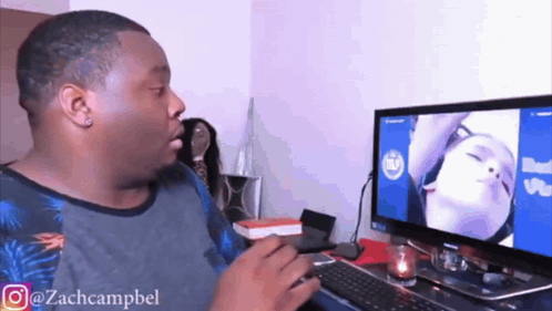 a man sitting in front of a computer with a picture of a woman on the screen ..