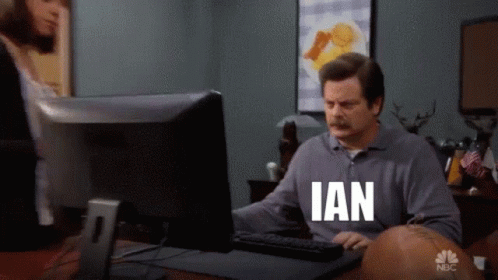 A Man Sitting In Front Of A Computer With Ian On His Shirt GIF