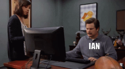 A Man Sitting In Front Of A Computer With The Word Ian Written On His Shirt GIF