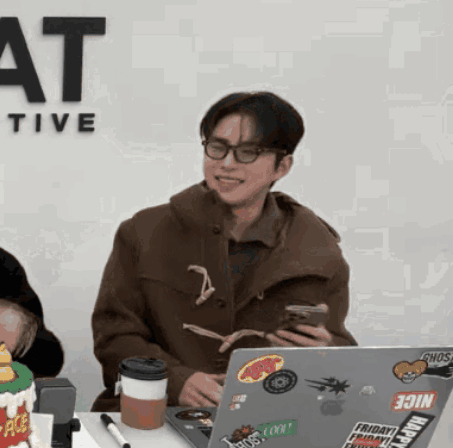 A Man Sitting In Front Of A Laptop With Stickers On It Including One That Says Join GIF