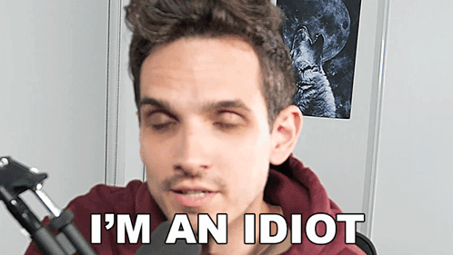 A Man Sitting In Front Of A Microphone With His Eyes Closed And The Words I 'M An Idiot Below Him GIF
