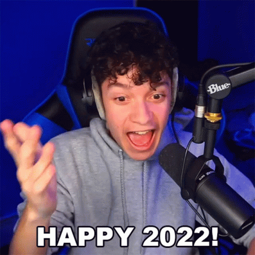 A Man Sitting In Front Of A Microphone With His Mouth Open And Says Happy 2022 GIF