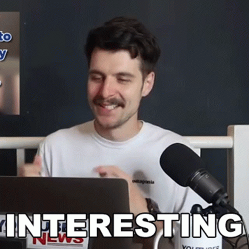 A Man Sitting In Front Of A Microphone With The Word Interesting Written On The Bottom GIF