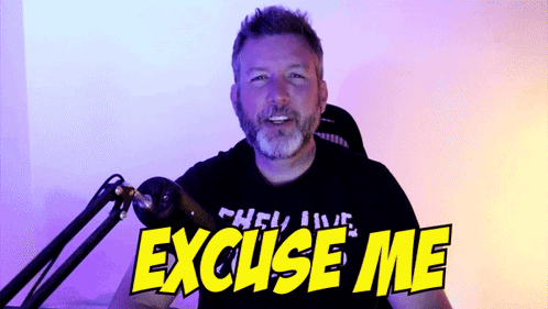 A Man Sitting In Front Of A Microphone With The Words " Excuse Me " On His Shirt GIF