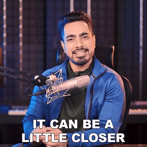 A Man Sitting In Front Of A Microphone With The Words It Can Be A Little Closer GIF