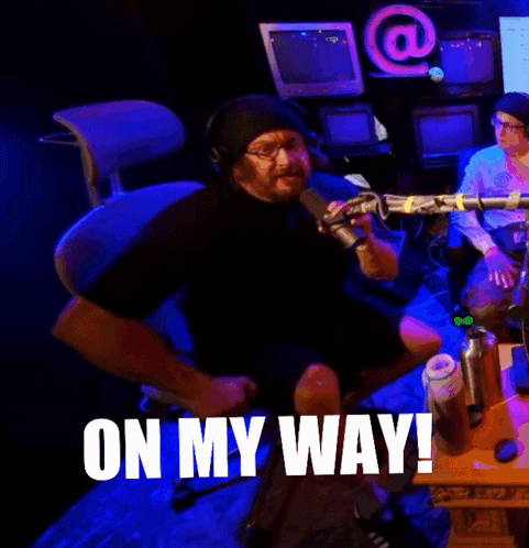 A Man Sitting In Front Of A Microphone With The Words On My Way Written On The Bottom GIF