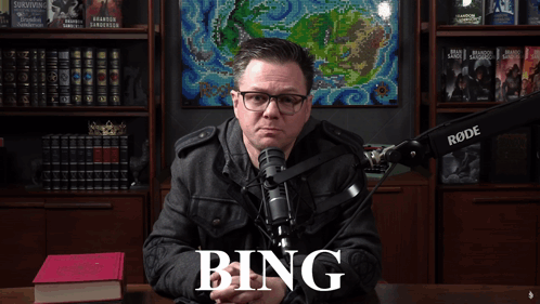 A Man Sitting In Front Of A Rode Microphone With The Word Bing On The Screen GIF