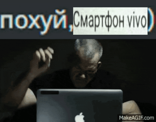 A Man Sitting In Front Of An Apple Laptop With A Makeagif.com Watermark On The Bottom GIF