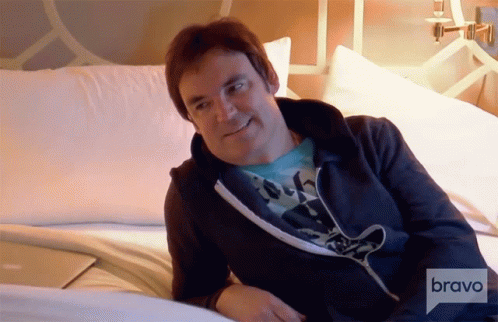 A Man Sitting On A Bed With Bravo Written On The Bottom Right GIF