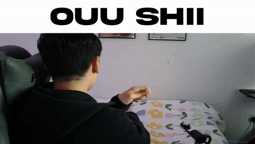 A Man Sitting On A Bed With The Words Ouu Shii Written Above Him GIF