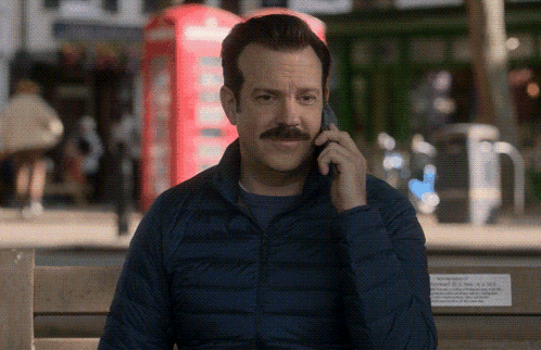 A Man Sitting On A Bench Talking On A Cell Phone GIF