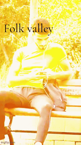 A Man Sitting On A Bench With The Word Folk Valley Written On The Bottom GIF