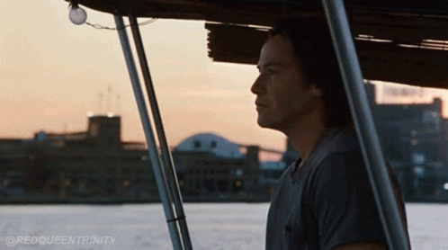 a man sitting on a boat looking out over a body of water with the hashtag @redqueentrinity