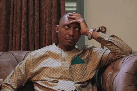 A Man Sitting On A Couch Covering His Face With His Hand GIF