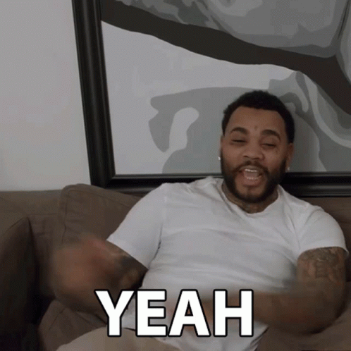 A Man Sitting On A Couch Says Yeah With His Arms Outstretched GIF