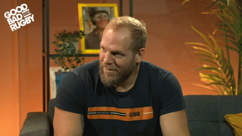A Man Sitting On A Couch Wearing A Gbr Shirt GIF