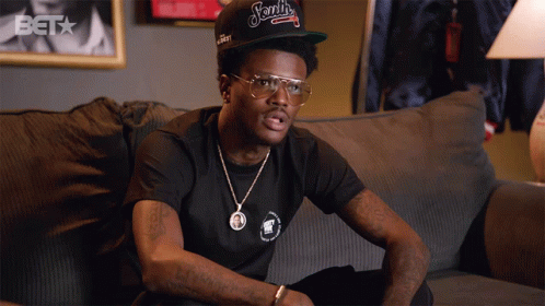 A Man Sitting On A Couch Wearing A Hat That Says ' Ford ' On It GIF