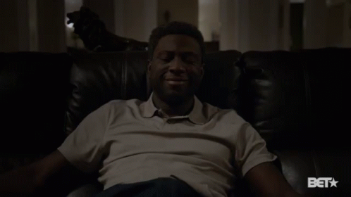 A Man Sitting On A Couch With A Bet Logo On The Bottom GIF