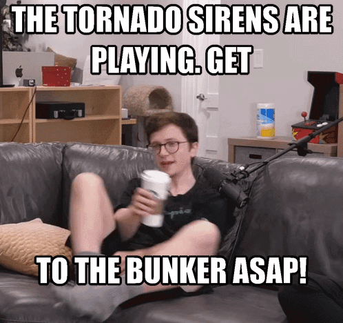 A Man Sitting On A Couch With A Cup Of Coffee And A Meme That Says The Tornado Sirens GIF
