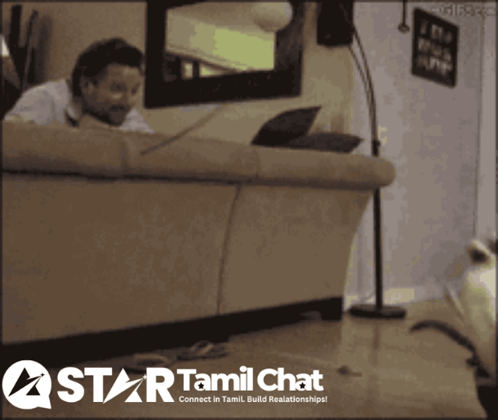 A Man Sitting On A Couch With A Laptop And A Star Tamil Chat Logo Behind Him GIF