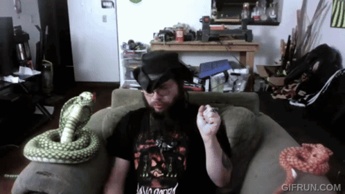 A Man Sitting On A Couch With A Snake And A Gif Run.com Logo GIF