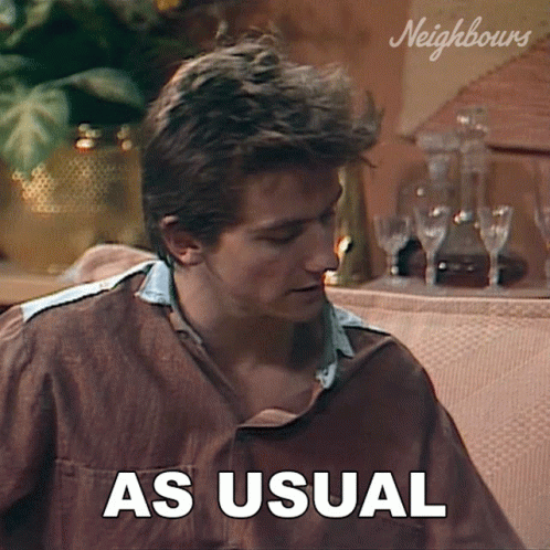 A Man Sitting On A Couch With The Words As Usual Written On The Screen GIF