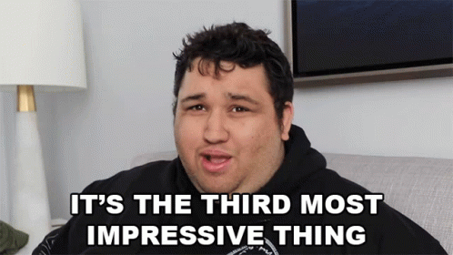 A Man Sitting On A Couch With The Words It 'S The Third Most Impressive Thing Above Him GIF