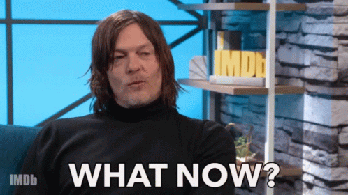 A Man Sitting On A Couch With The Words " What Now " On The Screen GIF