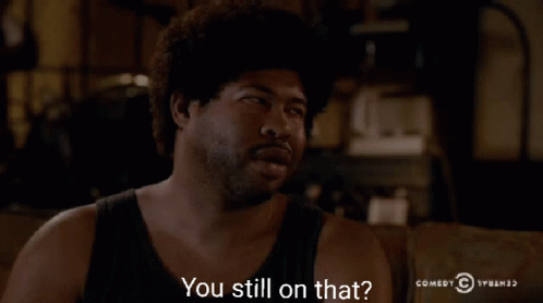 A Man Sitting On A Couch With The Words " You Still On That " In Front Of Him GIF