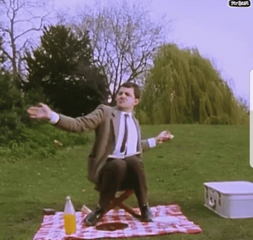 A Man Sitting On A Picnic Blanket With His Arms Outstretched GIF